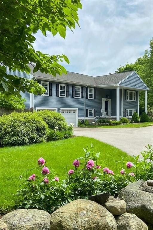 bi-level home with a front lawn, driveway, and an attached garage