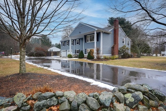 view of home's exterior with a garage, a yard, and a chimney