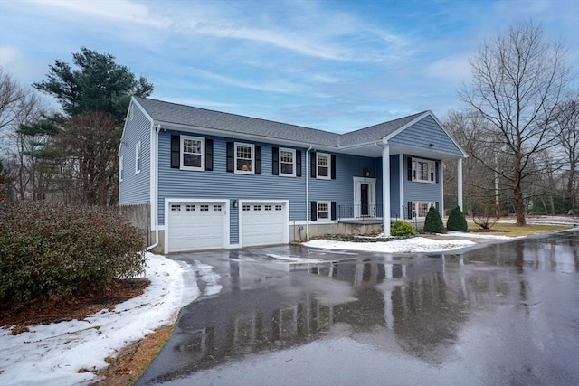 raised ranch featuring a garage and aphalt driveway