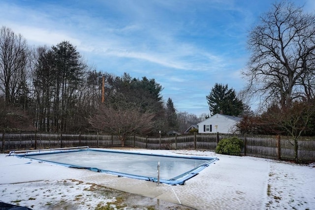 snow covered pool featuring fence and a fenced in pool