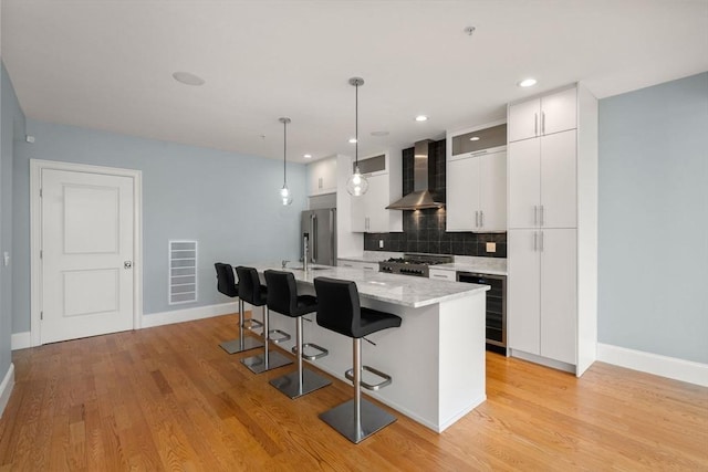 kitchen with wall chimney exhaust hood, stove, wine cooler, a breakfast bar, and backsplash