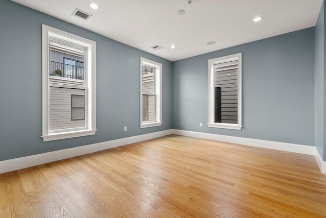 unfurnished room featuring baseboards, light wood-type flooring, plenty of natural light, and recessed lighting