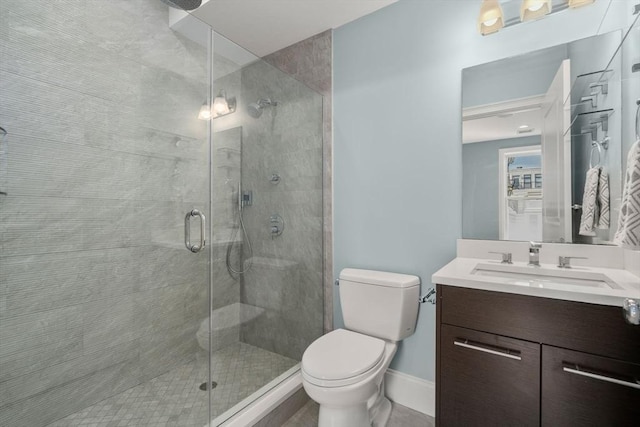 bathroom featuring a stall shower, toilet, vanity, and baseboards