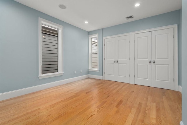 unfurnished bedroom with light wood-style floors, baseboards, recessed lighting, and a closet