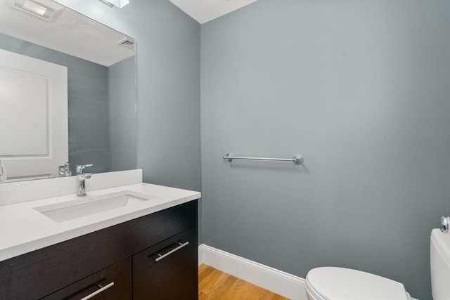 bathroom featuring toilet, wood finished floors, vanity, and baseboards