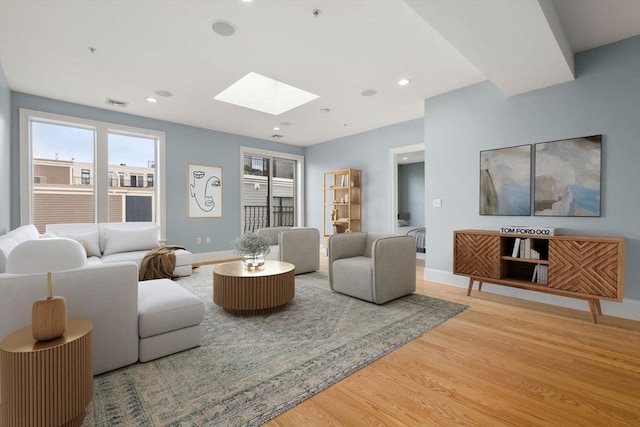 living area with a skylight, light wood-style floors, baseboards, and recessed lighting