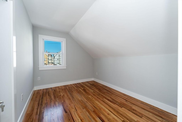 additional living space with lofted ceiling, baseboards, and wood finished floors