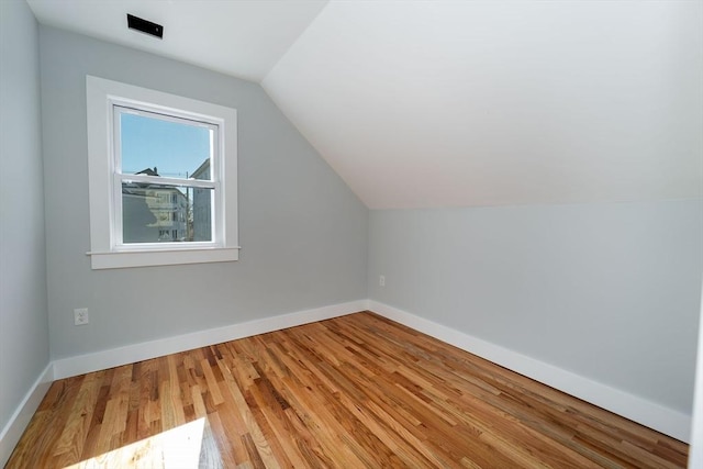 bonus room with baseboards, vaulted ceiling, and wood finished floors