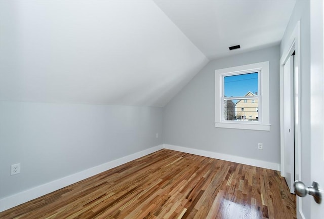 additional living space featuring vaulted ceiling, baseboards, and wood finished floors