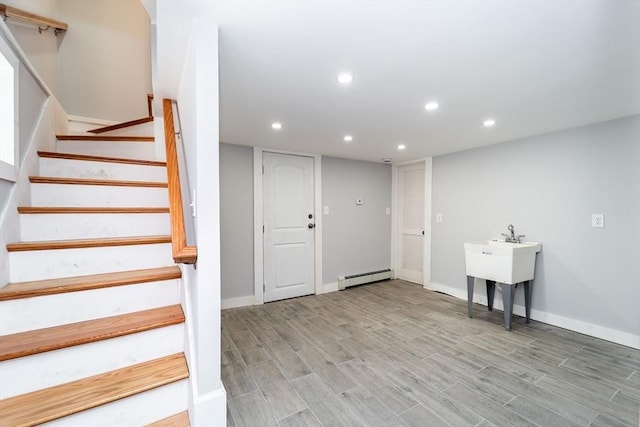 staircase featuring a baseboard heating unit, baseboards, wood finished floors, and recessed lighting