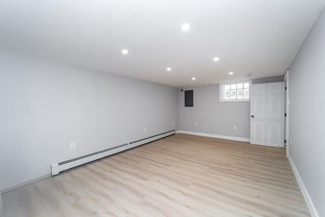 basement featuring recessed lighting, baseboard heating, light wood-type flooring, electric panel, and baseboards