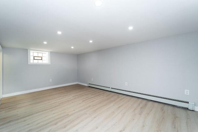 basement featuring a baseboard heating unit, light wood finished floors, baseboards, and recessed lighting