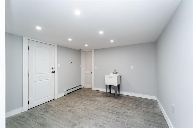 laundry area with a baseboard heating unit, light wood-style floors, baseboards, and recessed lighting