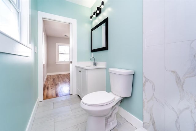 bathroom featuring toilet, vanity, and baseboards