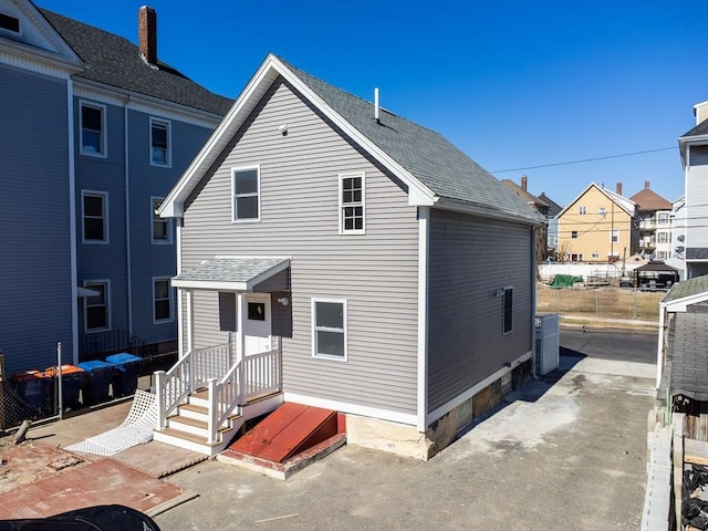 exterior space with a shingled roof and fence