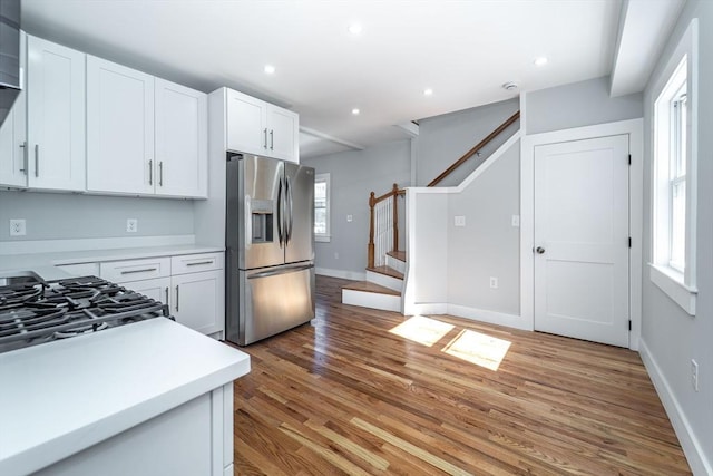 kitchen featuring light countertops, light wood finished floors, stainless steel fridge, and white cabinets