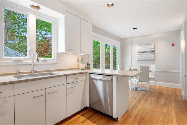 kitchen with light countertops, plenty of natural light, stainless steel dishwasher, and a sink