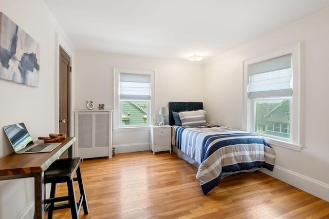 bedroom with crown molding, light wood-style flooring, and baseboards