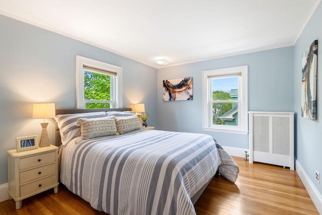 bedroom featuring baseboards, radiator, crown molding, and wood finished floors