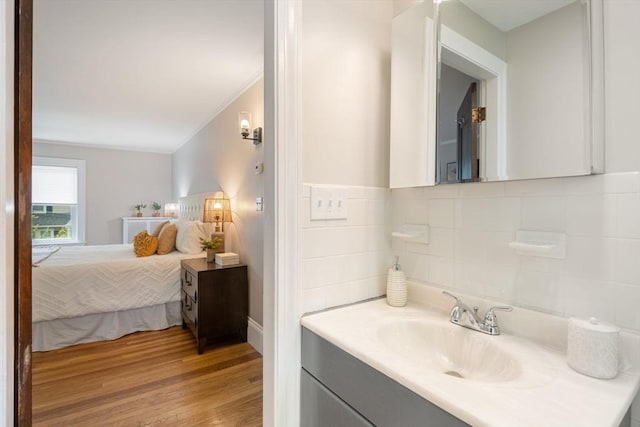 bathroom featuring baseboards, ornamental molding, vanity, wood finished floors, and tasteful backsplash