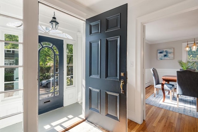 foyer entrance featuring crown molding, a chandelier, wood finished floors, and baseboard heating