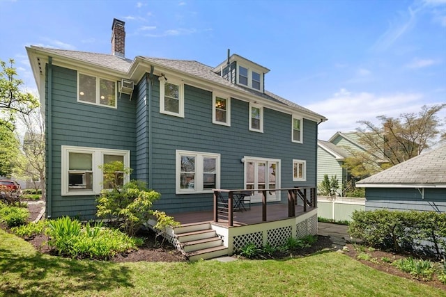 rear view of property featuring a wooden deck, a chimney, and a lawn