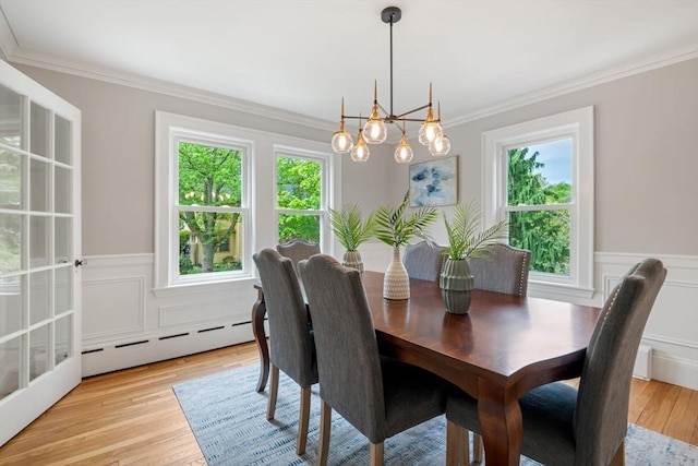 dining space with wainscoting, ornamental molding, a healthy amount of sunlight, and a baseboard heating unit