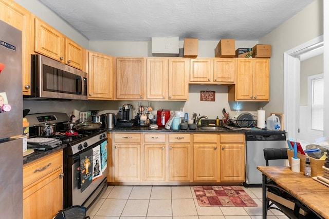 kitchen with light brown cabinets, a sink, stainless steel appliances, and light tile patterned floors