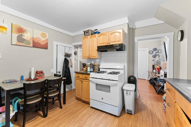 kitchen featuring dark countertops, white gas stove, under cabinet range hood, and light wood-style floors