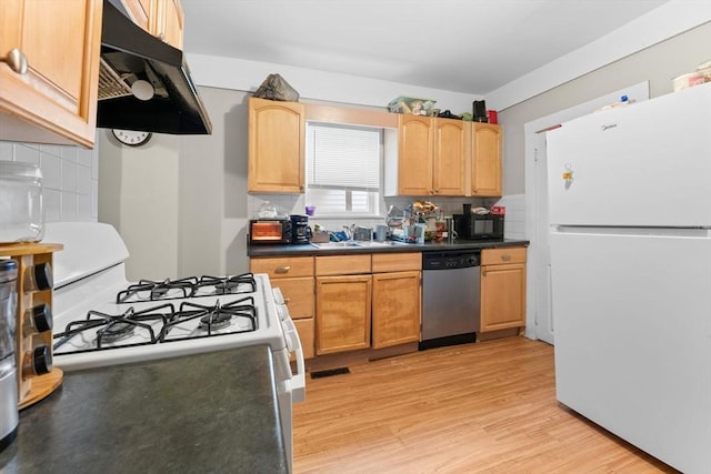 kitchen with dark countertops, tasteful backsplash, white appliances, light wood finished floors, and under cabinet range hood
