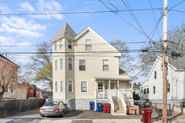 victorian house with a porch, fence, and a shingled roof