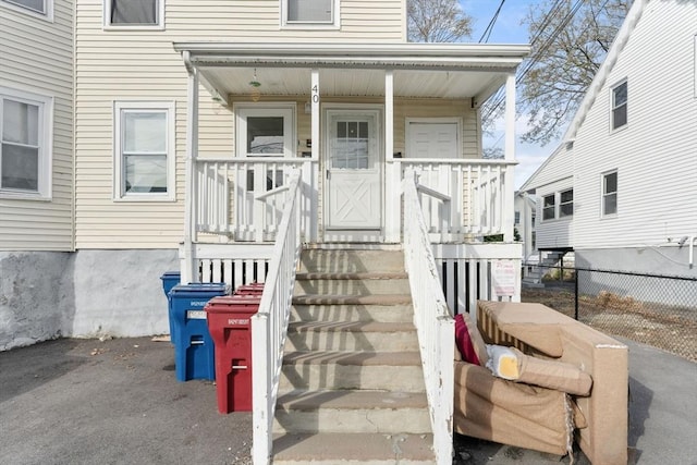 view of exterior entry with a porch and fence