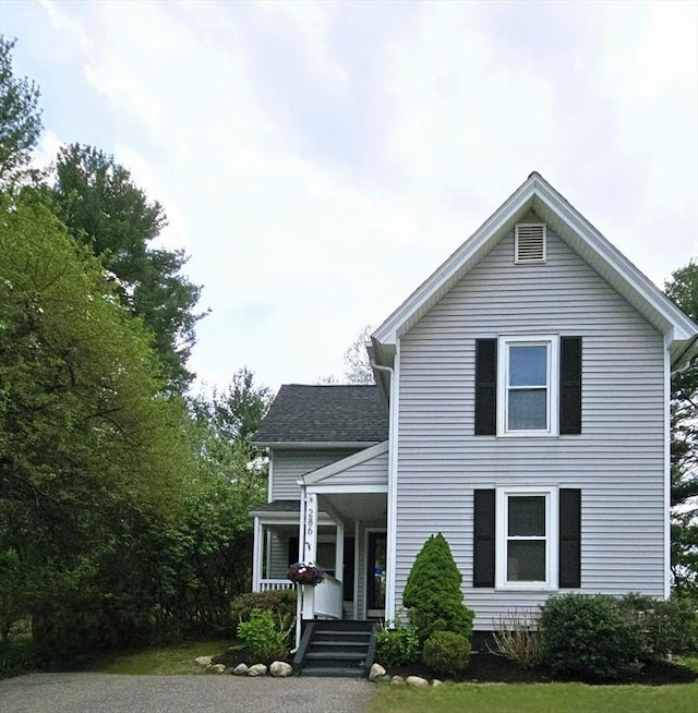 traditional home featuring a porch and roof with shingles