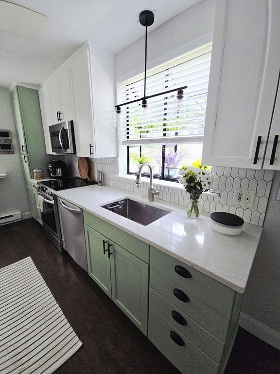 kitchen featuring a sink, appliances with stainless steel finishes, dark wood-style floors, tasteful backsplash, and white cabinetry
