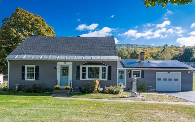 view of front of property featuring a garage, driveway, solar panels, a chimney, and a front lawn