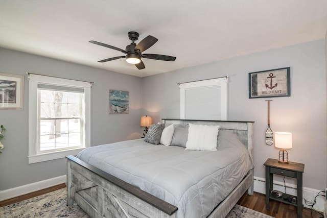 bedroom with a ceiling fan, baseboards, wood finished floors, and a baseboard heating unit