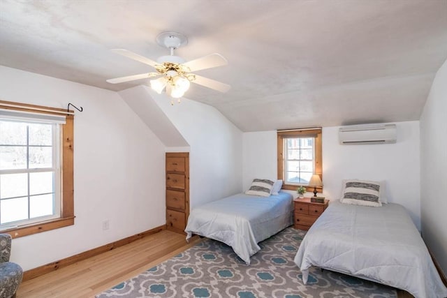 bedroom featuring lofted ceiling, wood finished floors, a ceiling fan, baseboards, and an AC wall unit