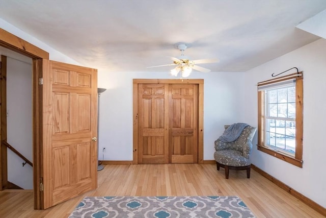 sitting room featuring baseboards, a ceiling fan, and light wood-style floors