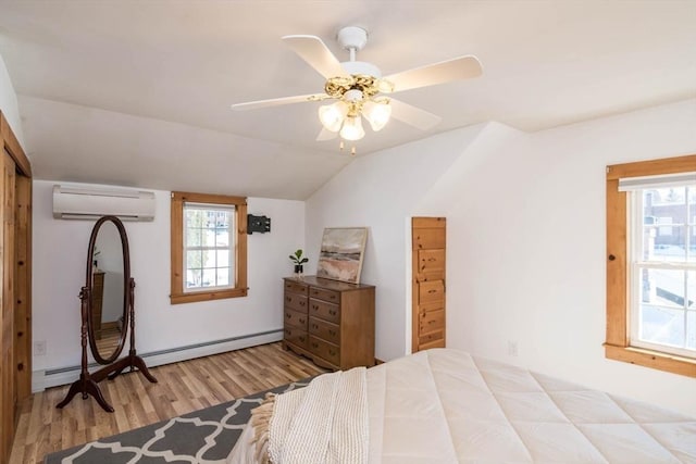 bedroom featuring lofted ceiling, ensuite bathroom, a baseboard heating unit, an AC wall unit, and wood finished floors