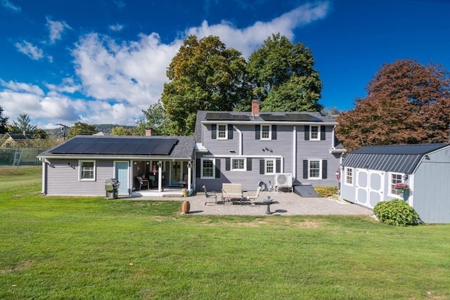 rear view of house featuring an outbuilding, a storage shed, a lawn, a chimney, and a patio area