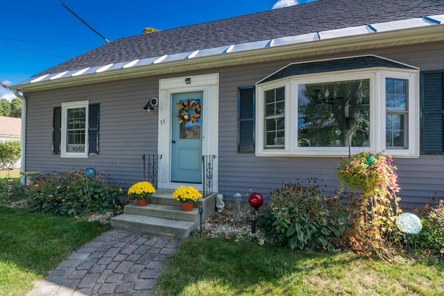 view of exterior entry featuring a shingled roof