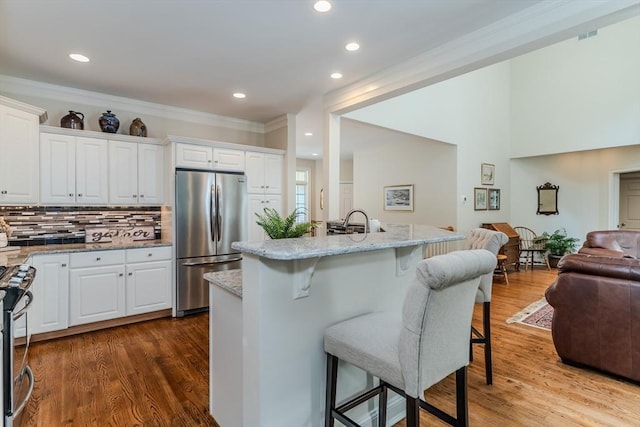 124 High Pine Cir Unit 124, Wilbraham, MA 01095 - kitchen featuring stainless steel appliances, open floor plan, a breakfast bar, ornamental molding, and decorative backsplash