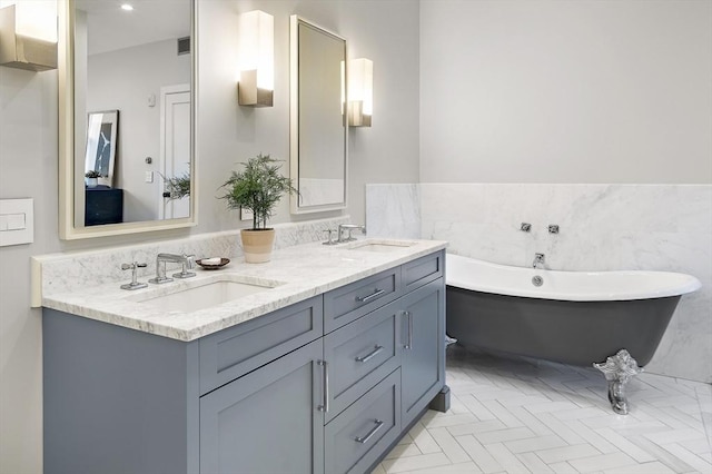 bathroom with a sink, tile walls, double vanity, and a freestanding bath