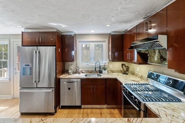 35 Merrymount Rd Unit 12, Quincy, MA 02169 - kitchen with stainless steel appliances, ventilation hood, a sink, light wood-style flooring, and light stone counters