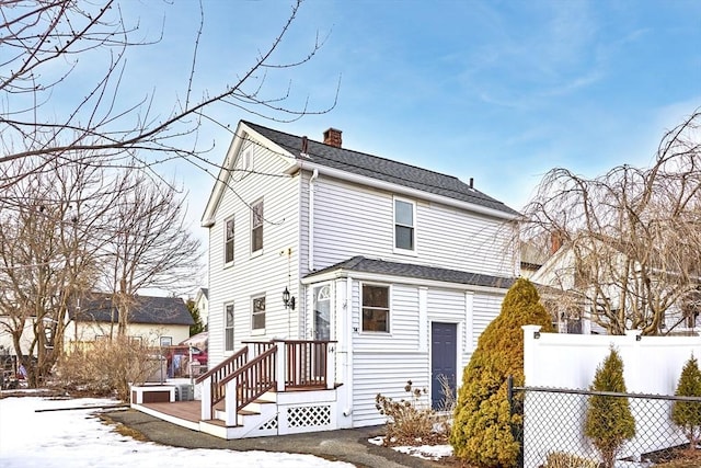 exterior space with roof with shingles, a chimney, and fence