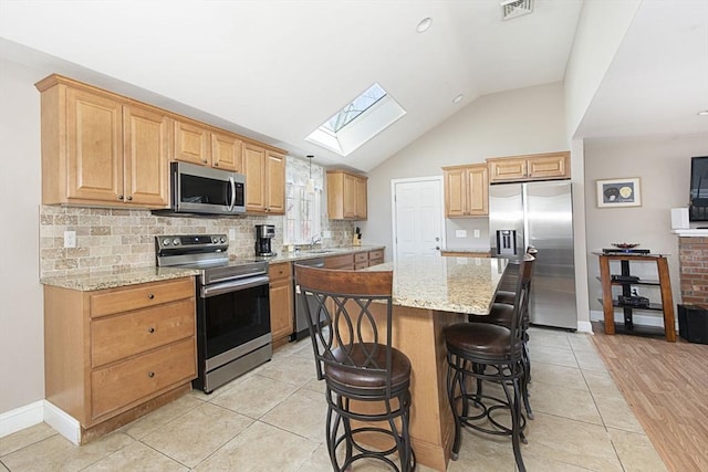 kitchen with light stone countertops, visible vents, a breakfast bar, a sink, and appliances with stainless steel finishes