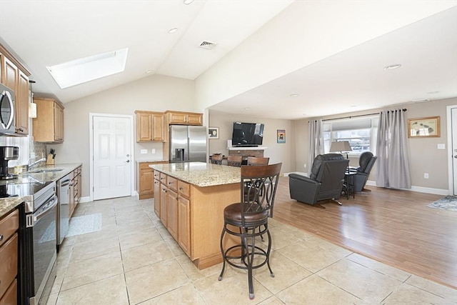 kitchen featuring visible vents, a breakfast bar, a kitchen island, appliances with stainless steel finishes, and light tile patterned floors