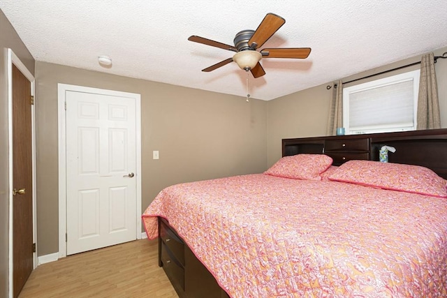 bedroom with a textured ceiling, a ceiling fan, and light wood finished floors