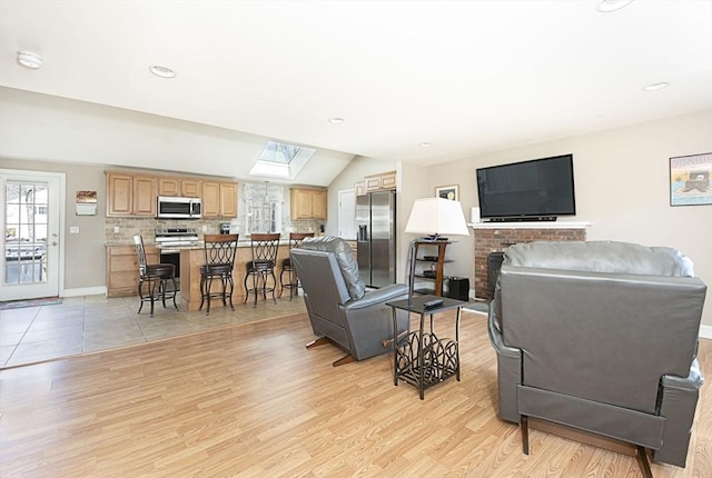 living area with lofted ceiling with skylight, recessed lighting, light wood-type flooring, and baseboards