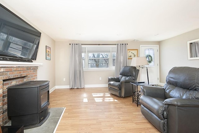 living room with light wood-type flooring, baseboards, and a wood stove